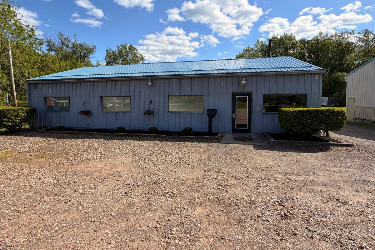 The front of the Fleet Herald install studio at 3920 12th St NW, Canton, OH 44708: a single-storey metal building with a blue roof above a gravel lot.